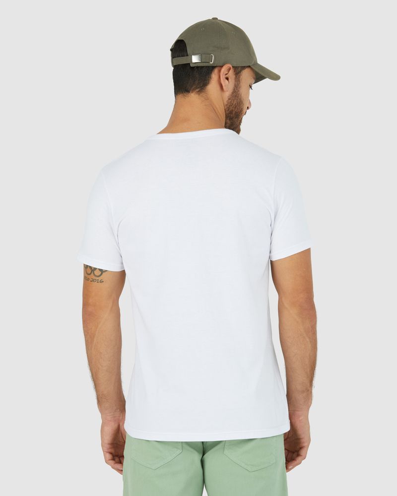 Homem branco com boné marrom e camiseta básica branca masculina com decote redondo e pesponto em algodão e short verde.