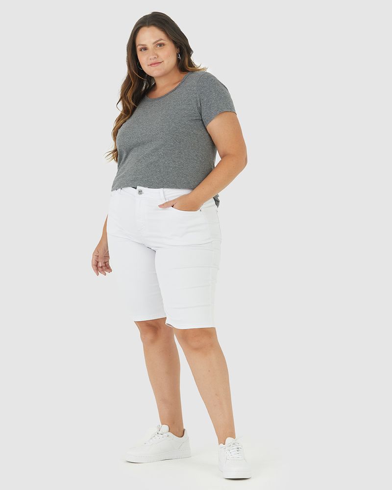 Mulher branca de cabelo castanho claro sorrindo e utilizando blusa básica plus size feminina, cor cinza com decote redondo em meia malha.