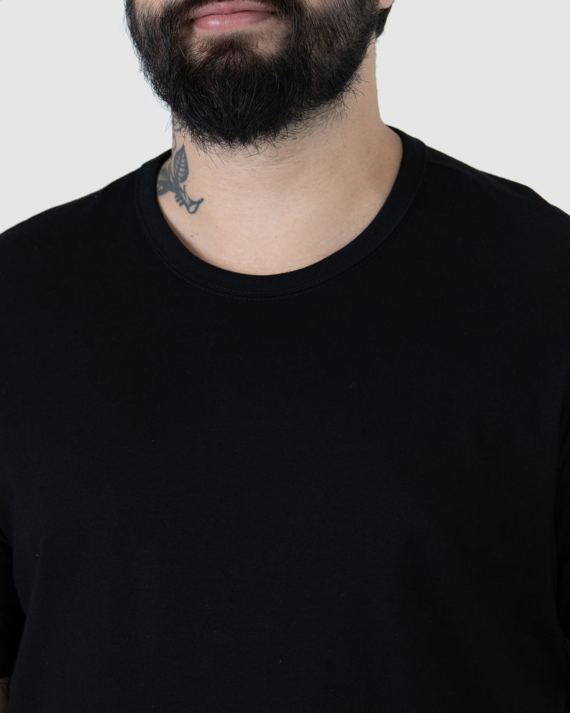 Homem branco com cabelo preto, de costas utilizando camiseta básica preta masculina plus size com decote redondo em algodão.