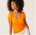 Mulher negra sorrindo usando blusa básica feminina laranja.